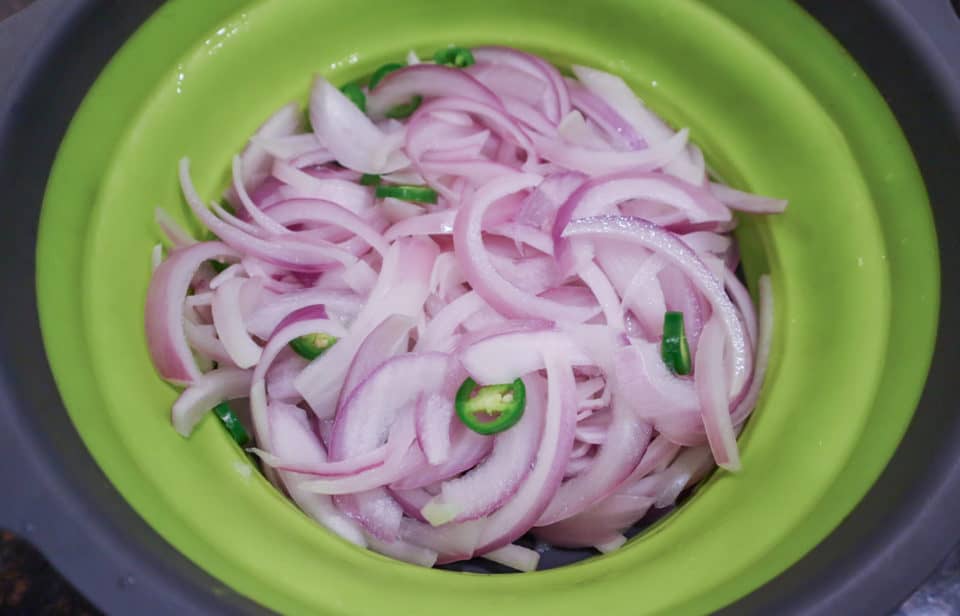 Drained onions and jalapenos in a colander for Quick Pickled Red Onions.