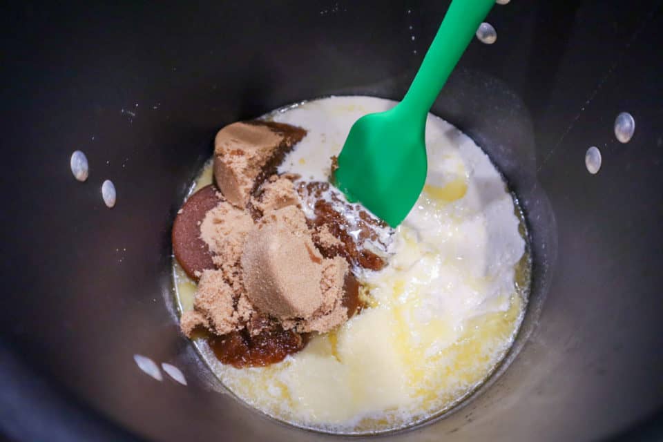 Brown sugar, butter, half & half and corn syrup in a pot before being mixed.  Green spatula in pot as well.