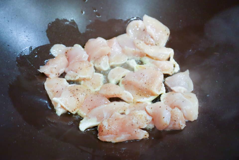 Uncooked, seasoned chicken pieces and oil in a skillet.
