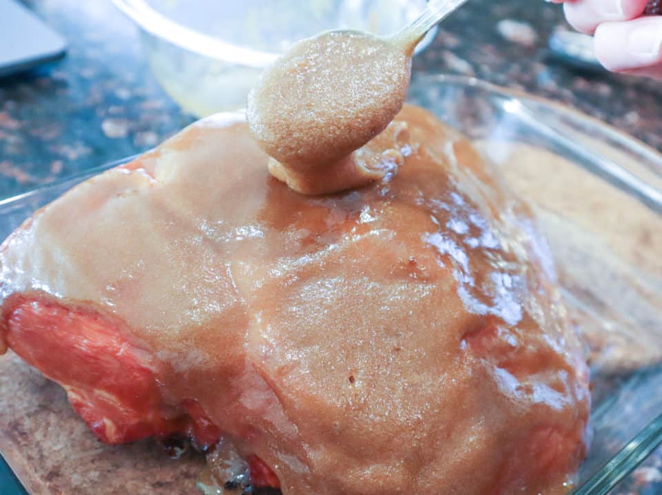 Easy Brown Sugar Glaze being spread over a ham.