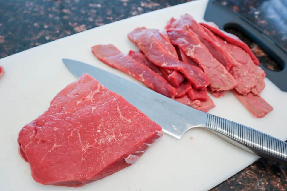 Beef being cut into jerky strips.