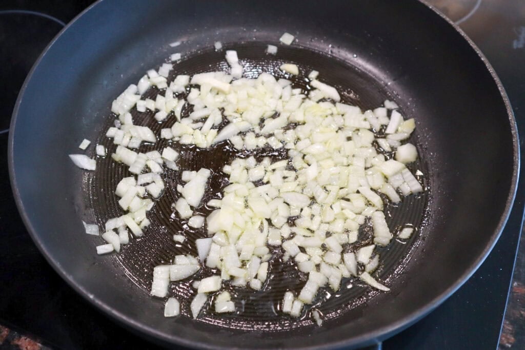 Softening onions in olive oil in a skillet.