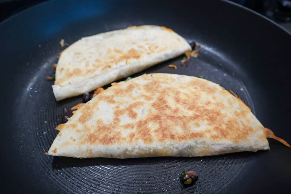 Slightly browned Assembled Pulled Pork Quesadillas in the skillet.