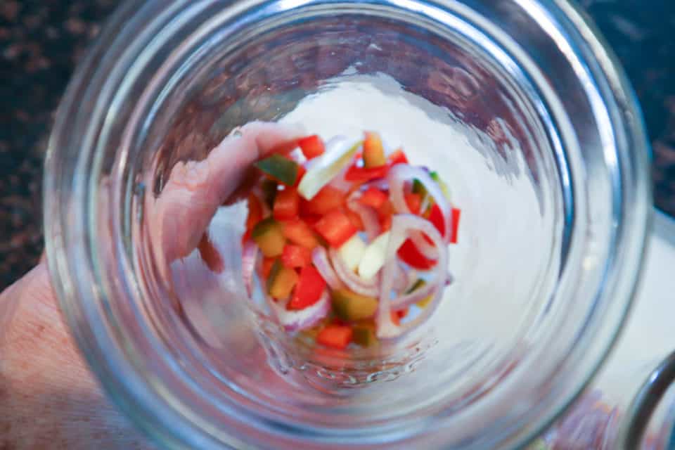 Peppers, onions and garlic in the bottom of a pint jar.