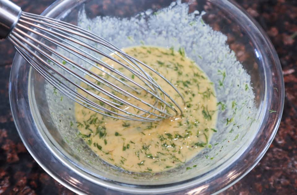 Whisking together ingredients for Dilly Dijon Vinaigrette in a small glass bowl.