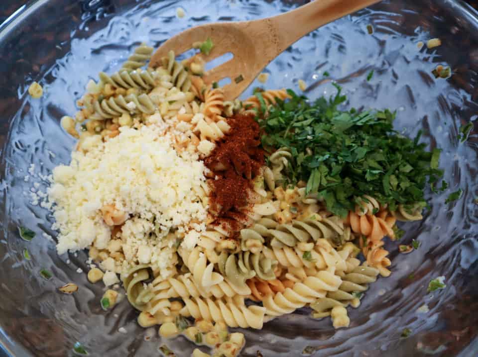 Adding cheese, cilantro and chili powder to the pasta and corn mixture