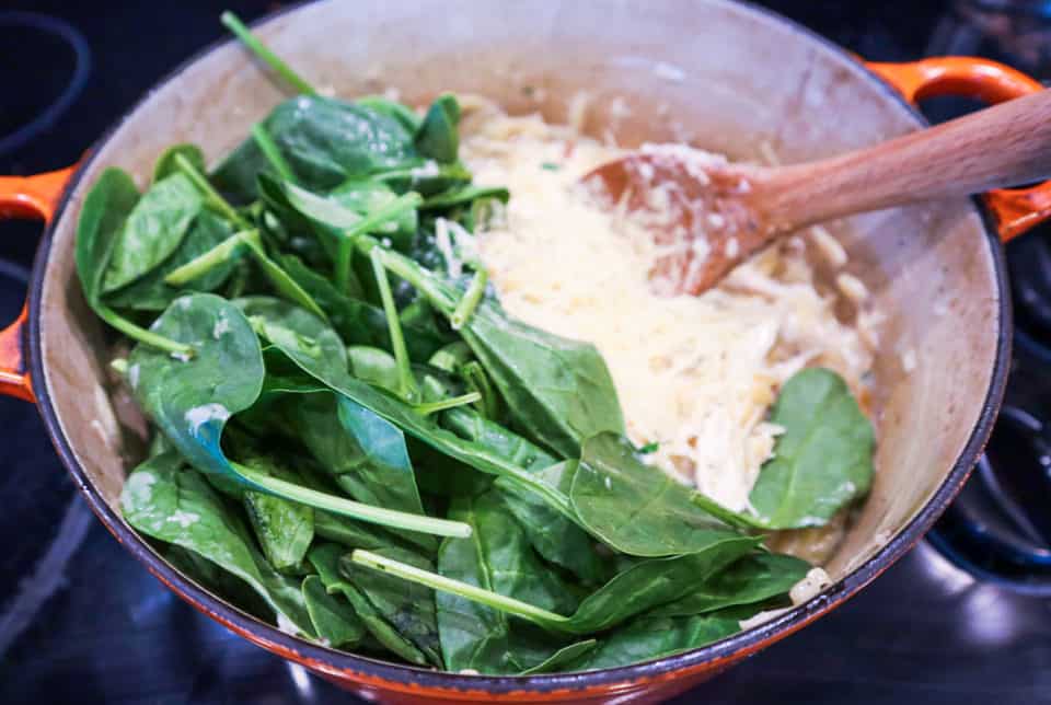 Adding spinach and Parmesan cheese to the pot.