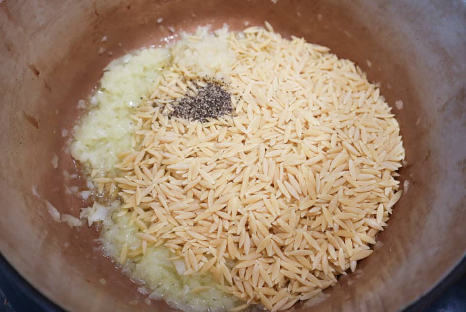 Orzo and black pepper being added to the pot.