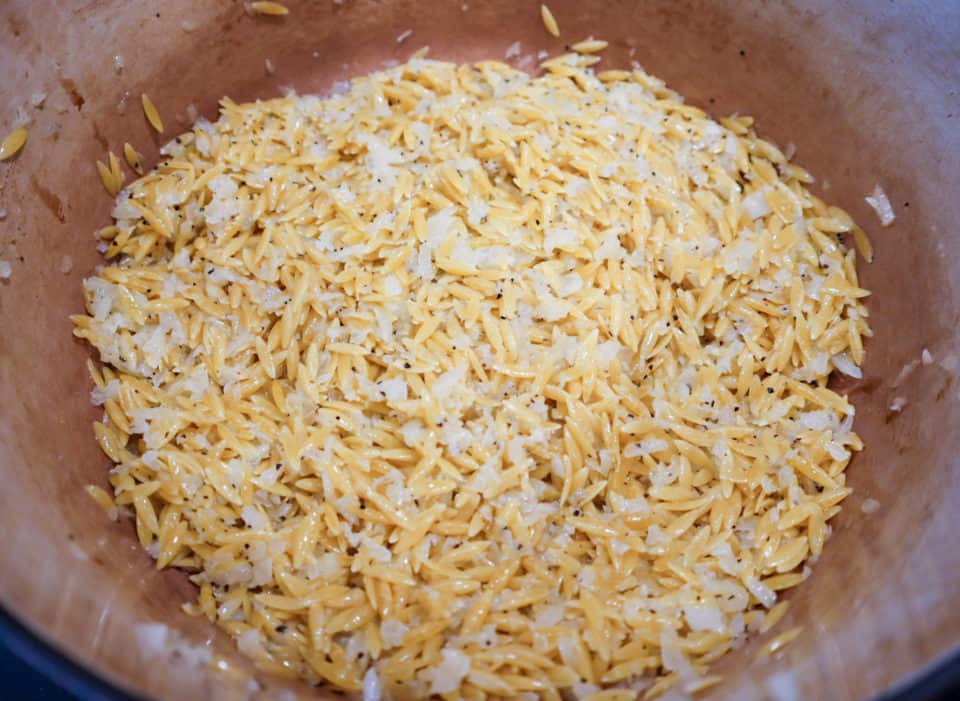 Slightly toasted orzo and other ingredients stirred together in a pot.