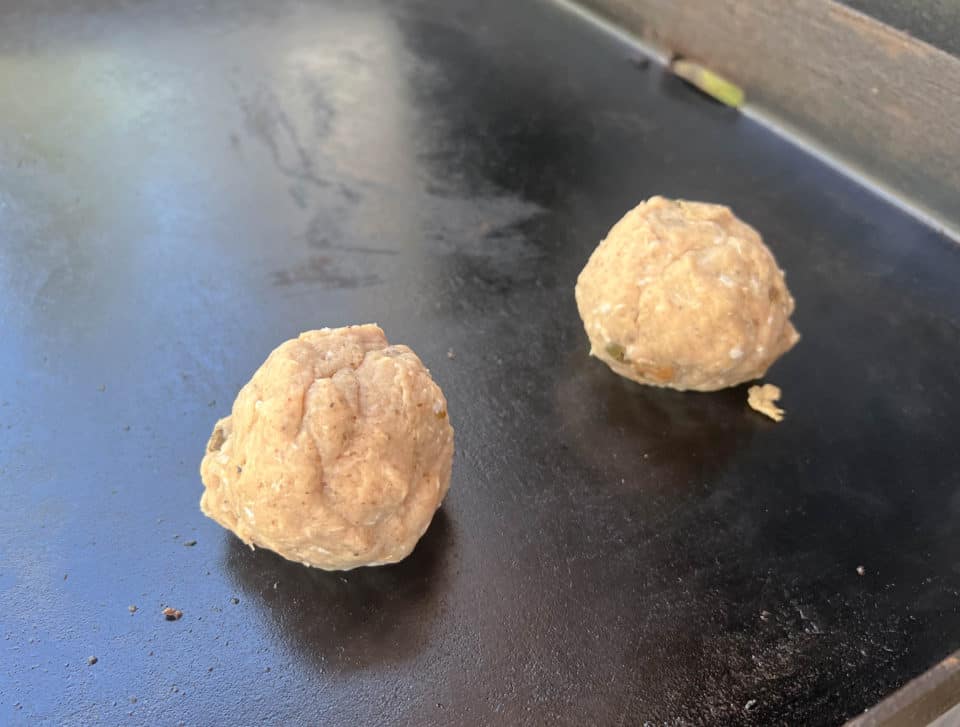 Mixed Ground Turkey Breakfast Sausage in balls on the griddle, prior to flattening.