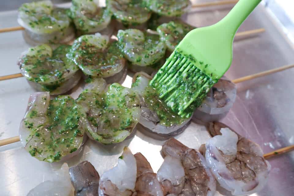 Shrimp being brushed with Fresh Lime Chimichurri Sauce before cooking.