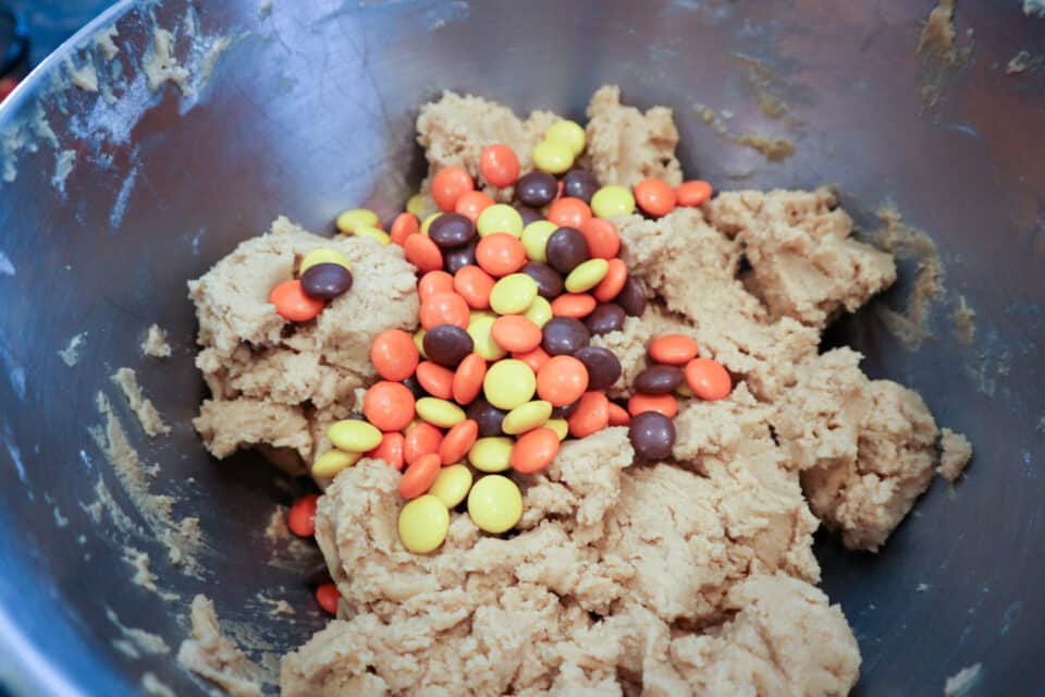 Reese's Pieces being added to the Peanut Butter Scoop Cookies.