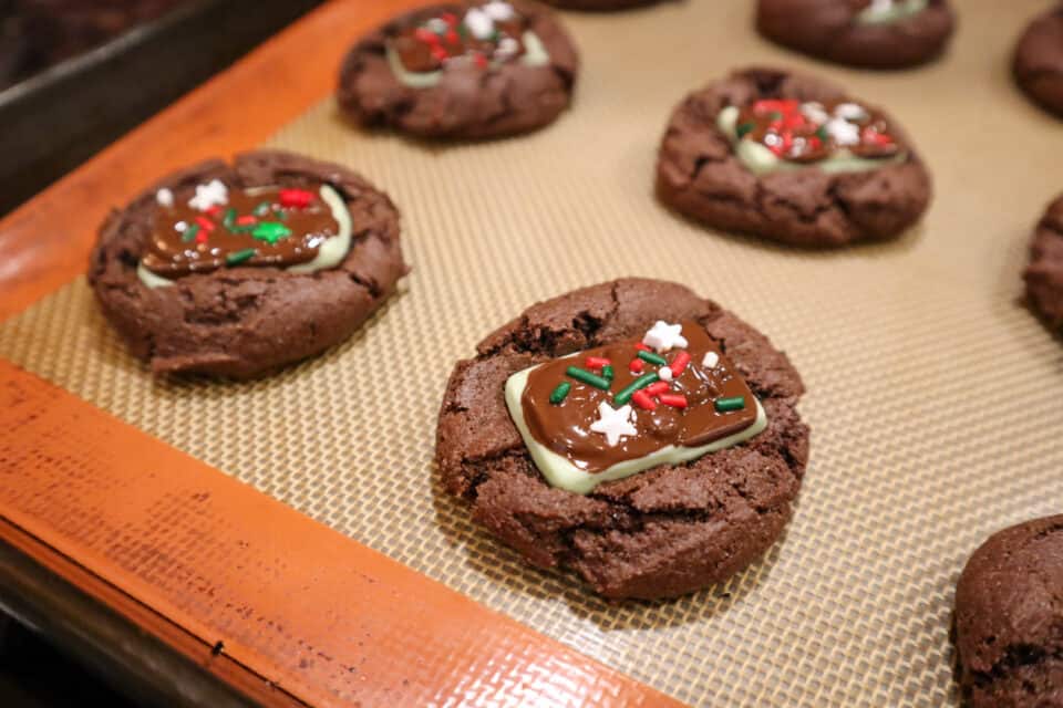 Decorating the Devil's Food Andes Mint Cookies with festive holiday sprinkles.