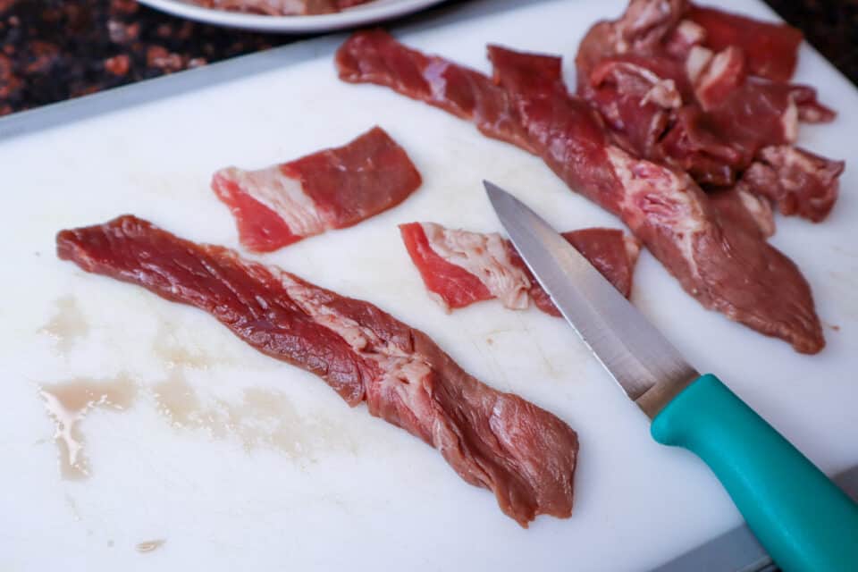 Beef strips being cut with a knife