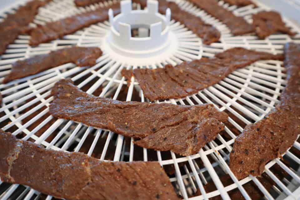 Marinated Worcestershire Beef Jerky strips on a dehydrator tray