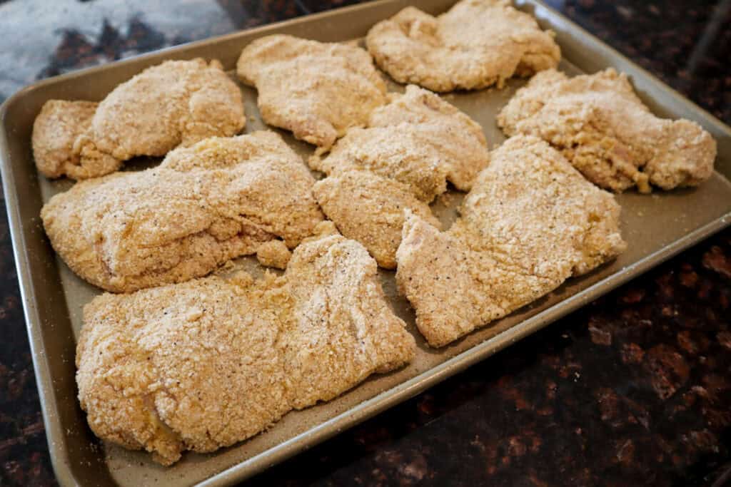 Breaded Dill Pickle Chicken Thighs on a baking sheet, ready to bake in the oven.