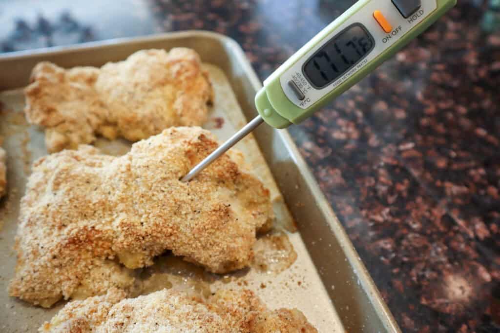 Dill Pickle Chicken Thighs cooked in the oven being temperature checked before serving.