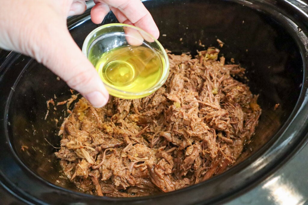 Pepperoncini juice being added to shredded Mississippi Pot Roast