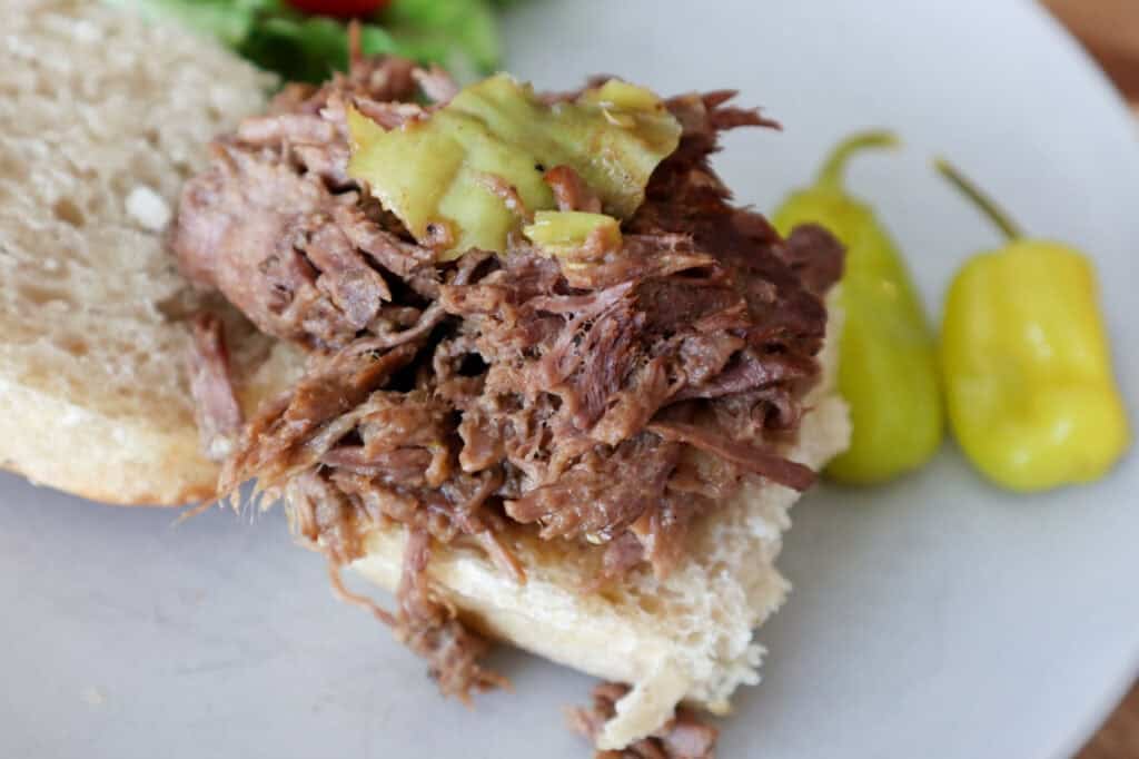 Mississippi Pot Roast piled high on a bun to be eaten as a sandwich.