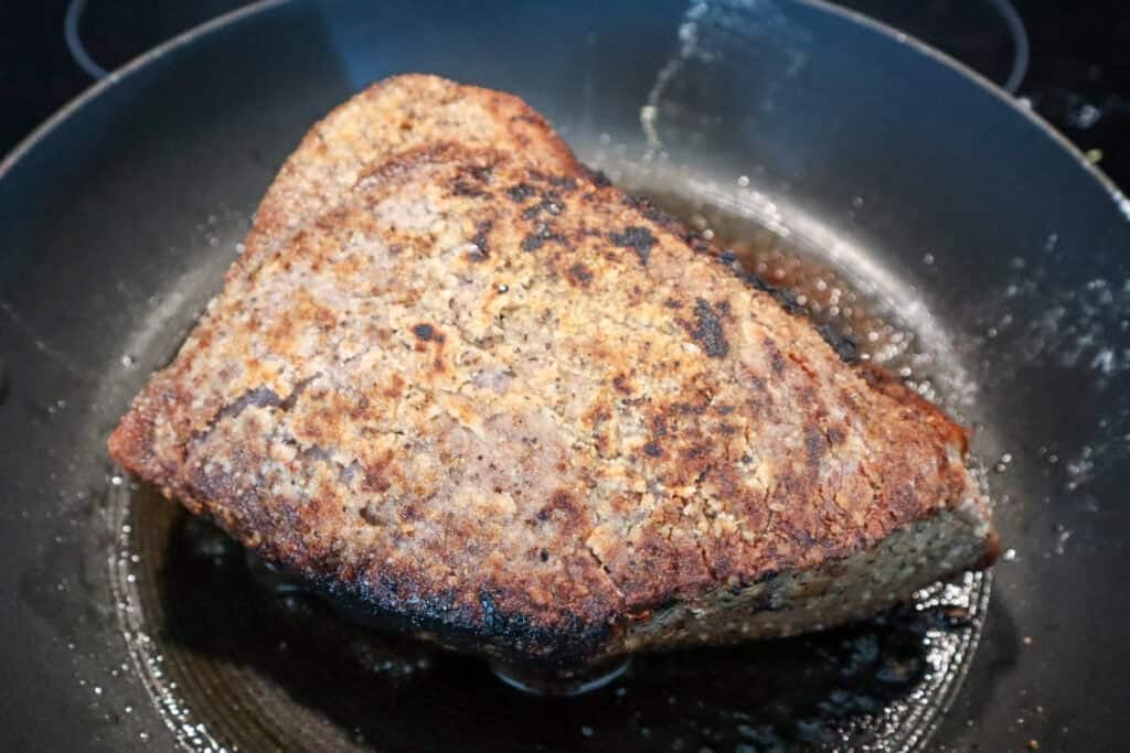 Creating a crust by browning the roast on all sides in a skillet.